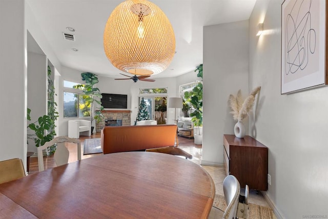 dining room with a stone fireplace and ceiling fan