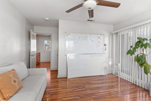 living room featuring dark wood-type flooring and ceiling fan