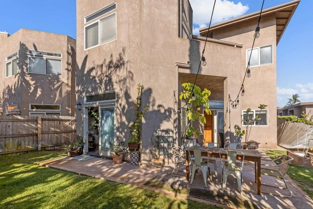 rear view of property with a patio and a lawn