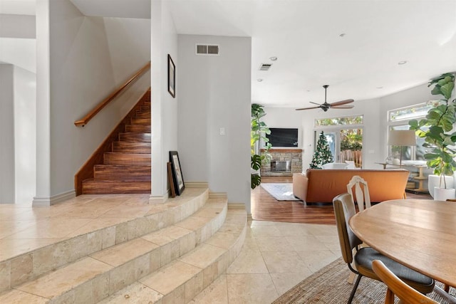 tiled dining area featuring a fireplace and ceiling fan