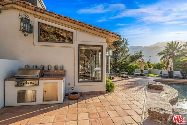 view of patio with a mountain view, grilling area, and exterior kitchen