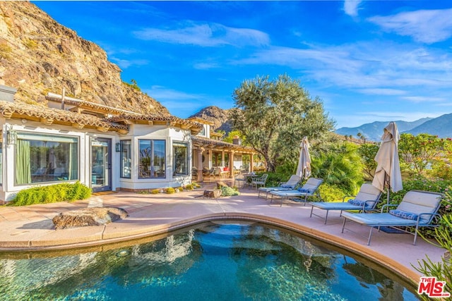 view of swimming pool with a mountain view and a patio area