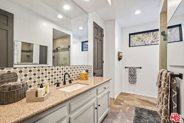 bathroom with vanity, walk in shower, and decorative backsplash