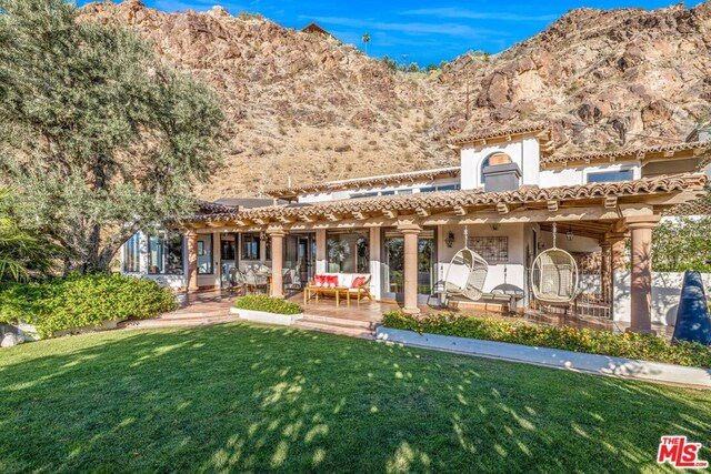 view of front of property featuring a mountain view, a patio area, and a front yard