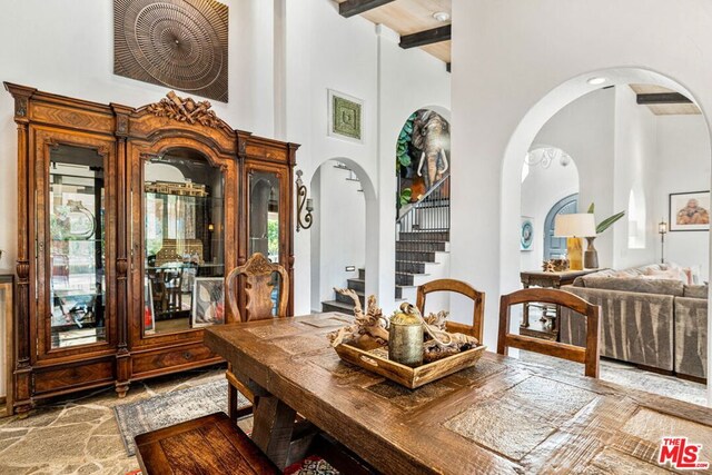 dining room featuring beamed ceiling and a high ceiling