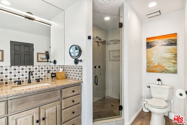 bathroom featuring an enclosed shower, vanity, wood-type flooring, decorative backsplash, and toilet