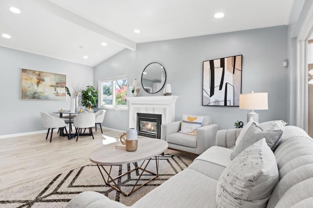 living room with lofted ceiling with beams, light hardwood / wood-style floors, and a premium fireplace