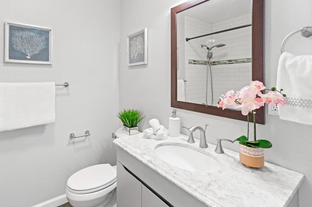 bathroom featuring vanity, tiled shower, and toilet