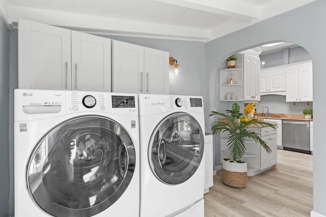 laundry area featuring sink, light hardwood / wood-style flooring, and washing machine and clothes dryer