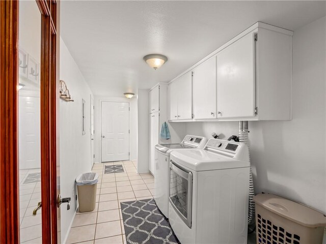 washroom featuring cabinets, washing machine and dryer, and light tile patterned floors