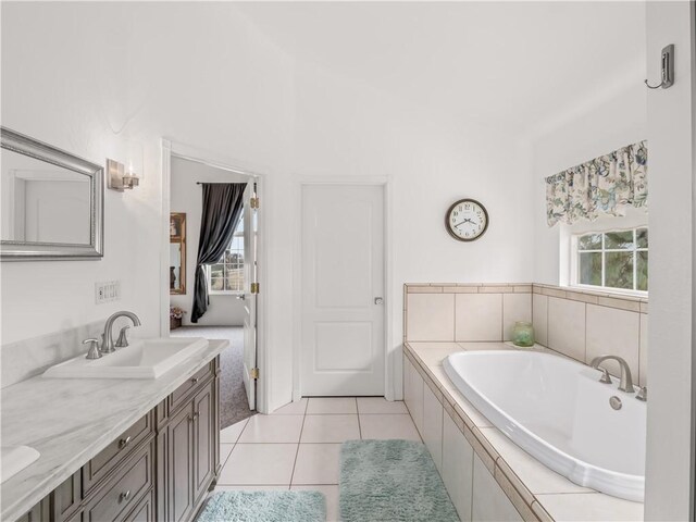 bathroom with tile patterned flooring, vanity, plenty of natural light, and a relaxing tiled tub