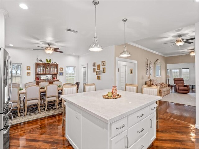 kitchen with stainless steel refrigerator, white cabinetry, dark hardwood / wood-style flooring, hanging light fixtures, and a center island