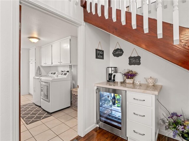 clothes washing area with separate washer and dryer, indoor bar, wine cooler, cabinets, and light tile patterned floors