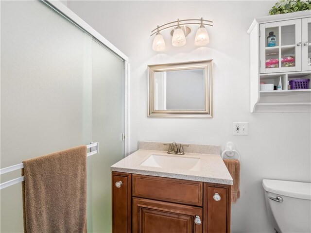 bathroom with walk in shower, vanity, and toilet