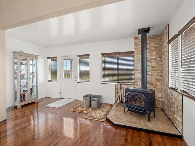 entrance foyer featuring brick wall, wood-type flooring, and a wood stove