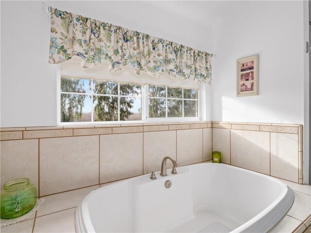 bathroom with a healthy amount of sunlight and tiled bath