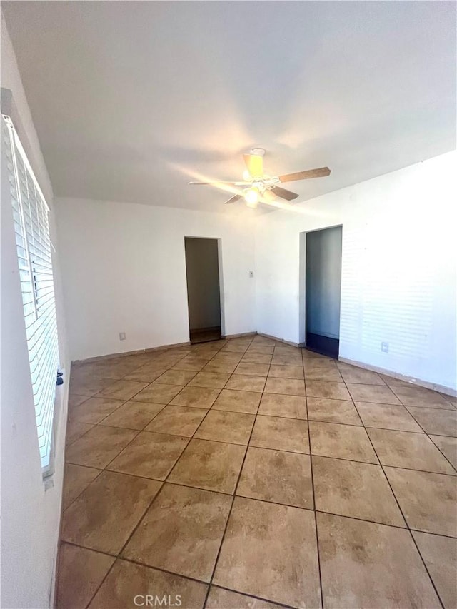 tiled spare room with ceiling fan