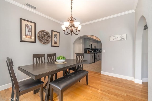 dining area with a notable chandelier, light hardwood / wood-style flooring, and ornamental molding