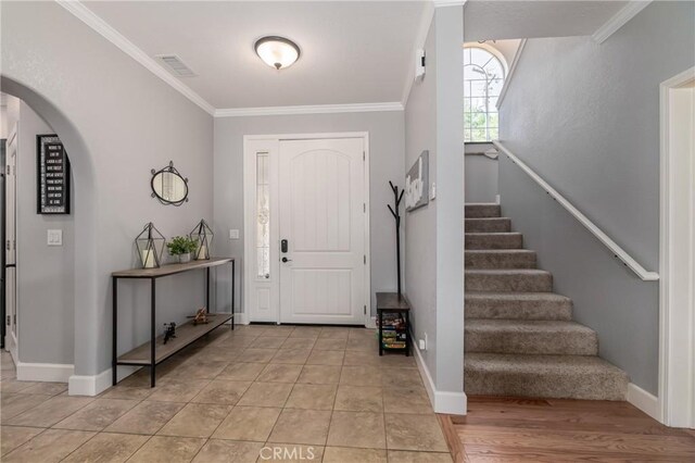 foyer entrance with ornamental molding and light tile patterned flooring