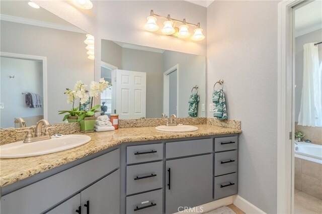 bathroom featuring tiled tub, crown molding, and vanity