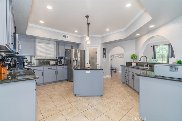 kitchen featuring pendant lighting, sink, stainless steel fridge, backsplash, and a center island