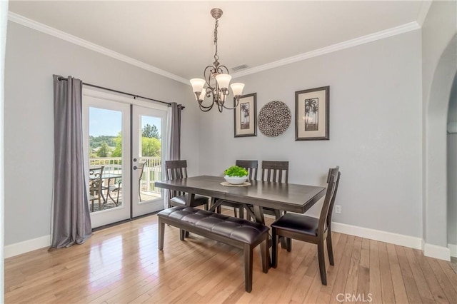 dining space featuring crown molding, light hardwood / wood-style flooring, an inviting chandelier, and french doors