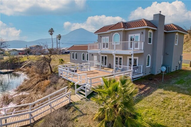 back of property featuring french doors, a balcony, a yard, and a mountain view