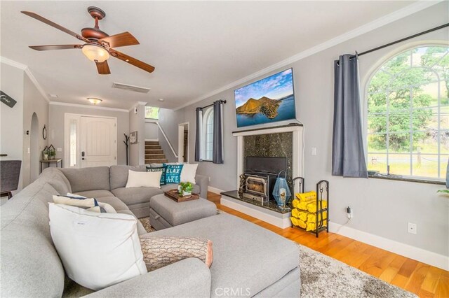 living room featuring crown molding, a wood stove, and hardwood / wood-style floors