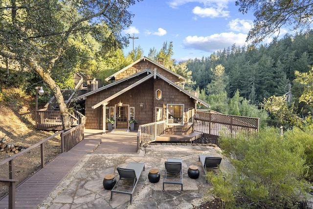 rear view of house with a wooden deck and a patio area