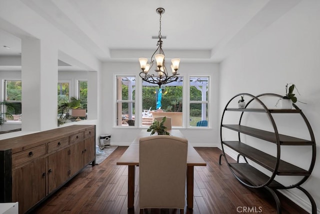 dining room with dark hardwood / wood-style floors, a tray ceiling, and a chandelier