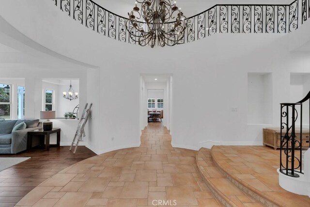 entryway with an inviting chandelier, a towering ceiling, and a healthy amount of sunlight