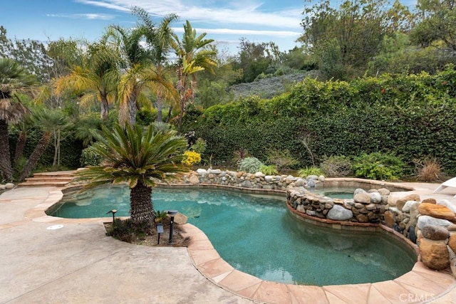 outdoor pool with a patio area and an in ground hot tub