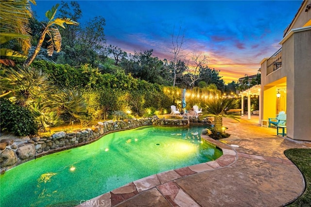 pool at dusk featuring a patio area