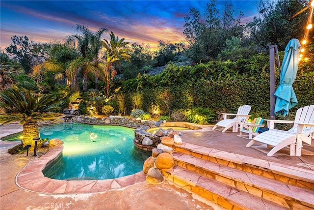 pool at dusk featuring a patio area