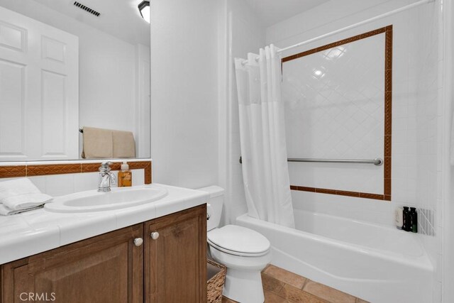 bathroom with visible vents, toilet, vanity, shower / tub combo with curtain, and backsplash