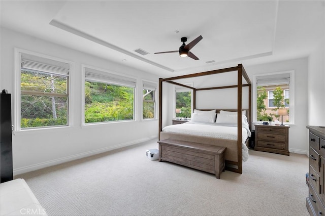 bedroom with light carpet, a raised ceiling, and ceiling fan