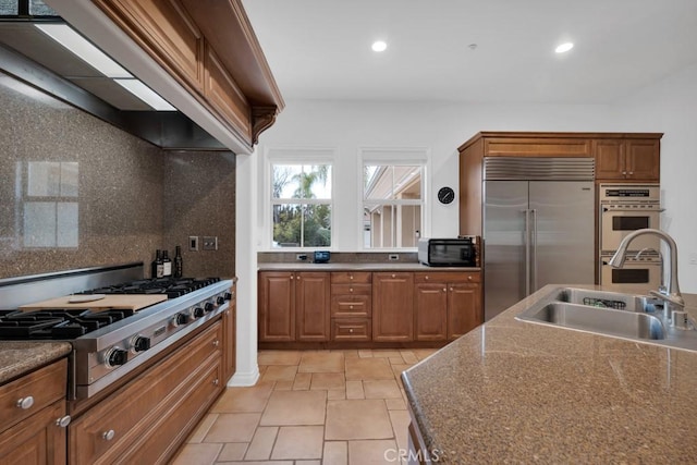 kitchen featuring tasteful backsplash, sink, stone counters, and appliances with stainless steel finishes