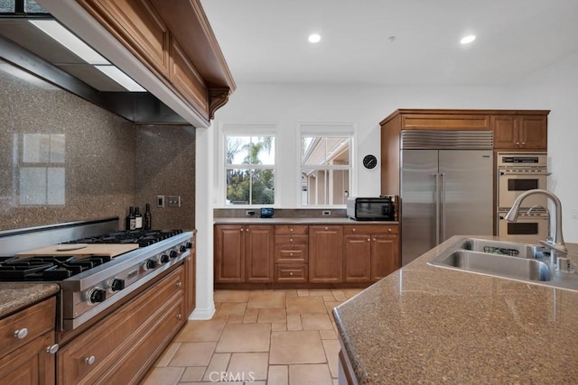 kitchen featuring brown cabinetry, a sink, recessed lighting, and appliances with stainless steel finishes
