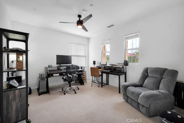 carpeted office space featuring baseboards, visible vents, and ceiling fan