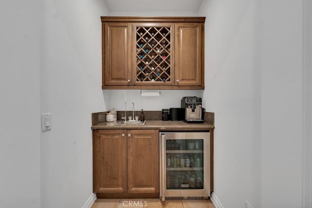 bar with sink, light tile patterned floors, and beverage cooler