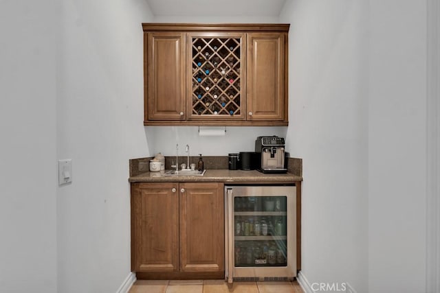 bar featuring wet bar, a sink, baseboards, and beverage cooler