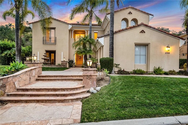 mediterranean / spanish house with a balcony and a yard