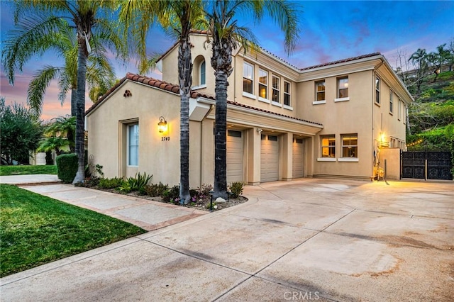 mediterranean / spanish house featuring a tiled roof, concrete driveway, stucco siding, and an attached garage