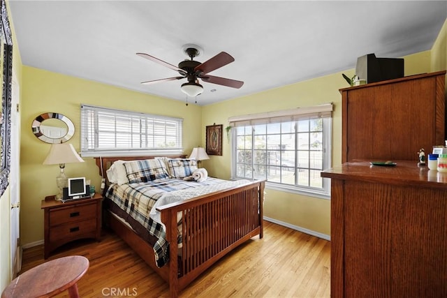 bedroom with multiple windows, light wood-style flooring, and baseboards