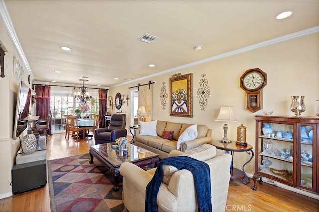 living room featuring ornamental molding, wood finished floors, visible vents, and a barn door