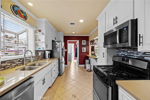 kitchen with a sink, light countertops, ornamental molding, appliances with stainless steel finishes, and open shelves