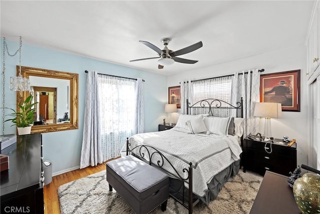 bedroom with light wood-style floors, ceiling fan, and baseboards