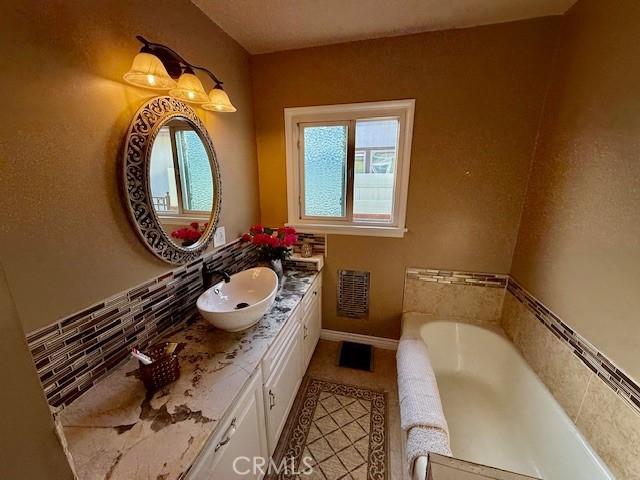 full bathroom featuring a garden tub, visible vents, baseboards, and vanity