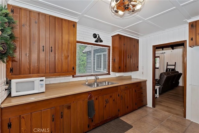 kitchen featuring coffered ceiling, sink, and light tile patterned floors