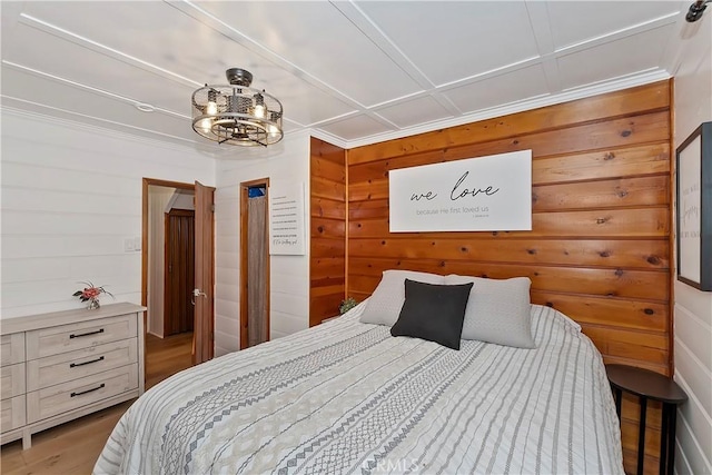 bedroom featuring wood-type flooring, a notable chandelier, and wood walls